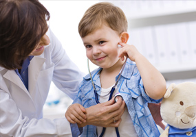 A young boy trying out the doctor's stethascope'